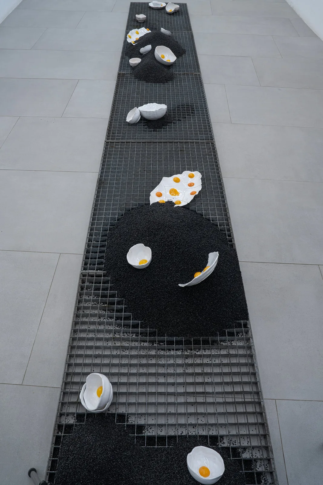 Katharina Maderthaner, Sondierschnitt, 2023. Ceramic, gravel, metal grids · 500 × 70 × 30 cm